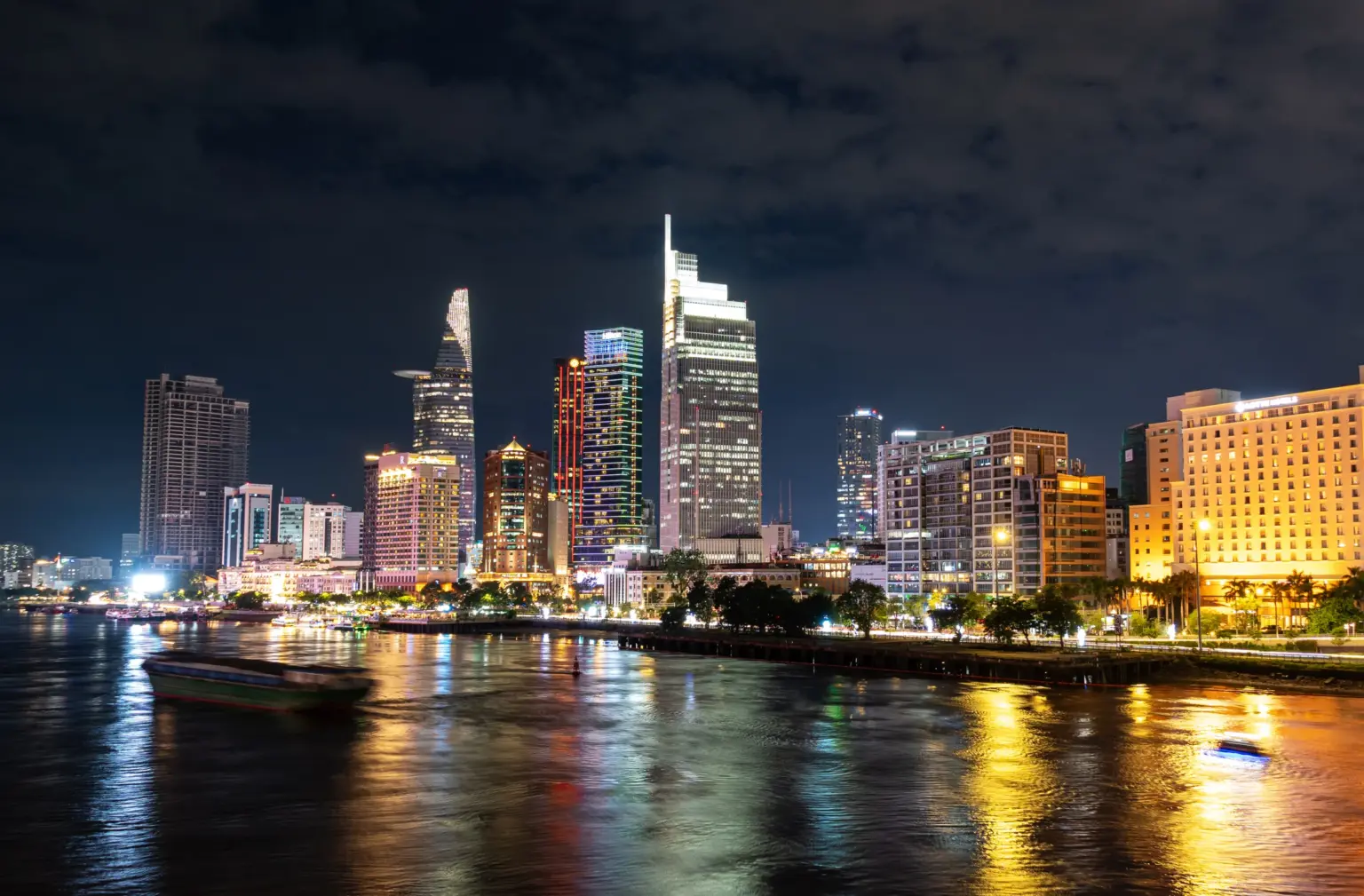 District 1 skyline in Ho Chi Minh City with Bitexco Financial Tower and illuminated high-rise buildings beside the Saigon River